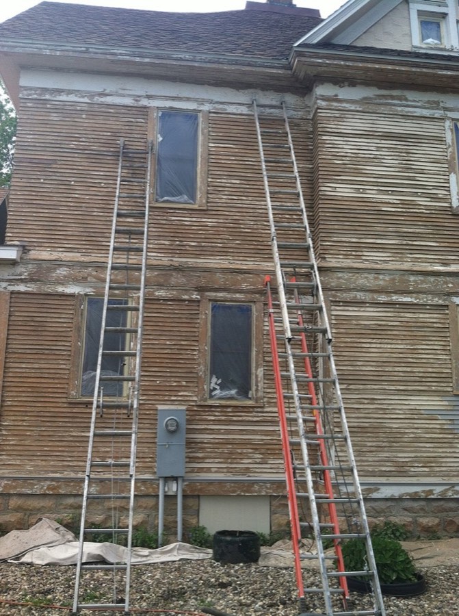 Weathered siding with peeling paint on a two-storey house