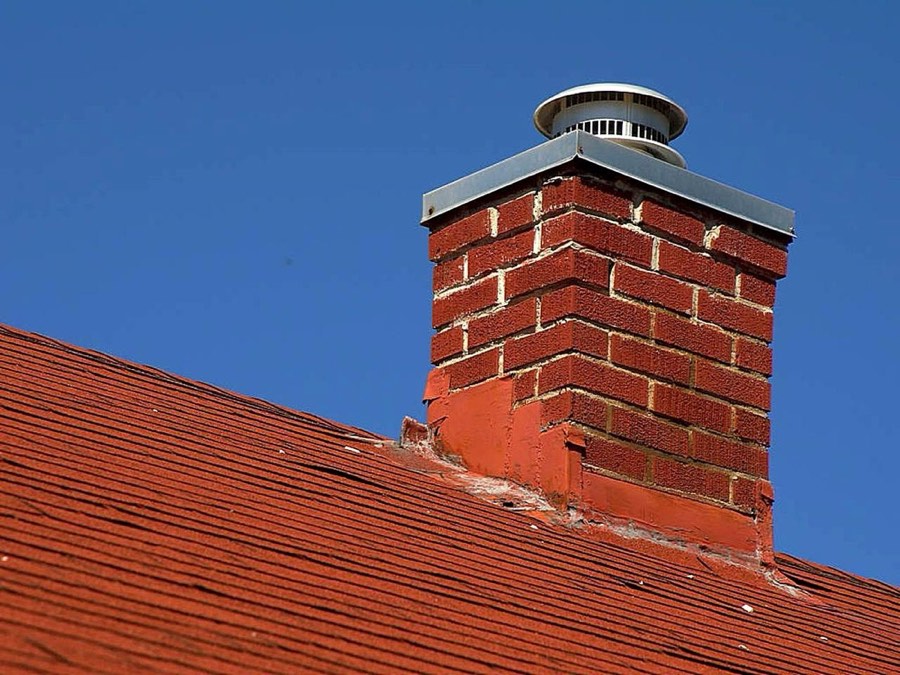 Brick chimney with metal cap on a pitched roof
